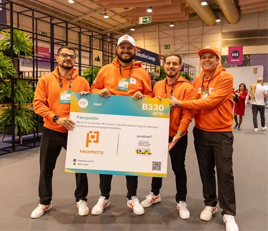 Equipe Faceponto segurando a placa do estande em um evento de tecnologia